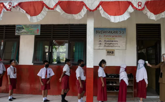 Guru memeriksa suhu tubuh siswanya sebelum mengikuti Kegiatan Belajar Mengajar tatap muka di SD Negeri 26 Sukajadi